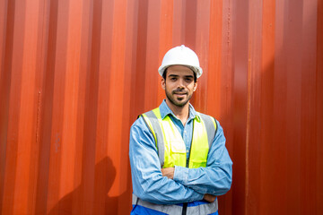 Portrait of confident young hispanic male engineer with container background.