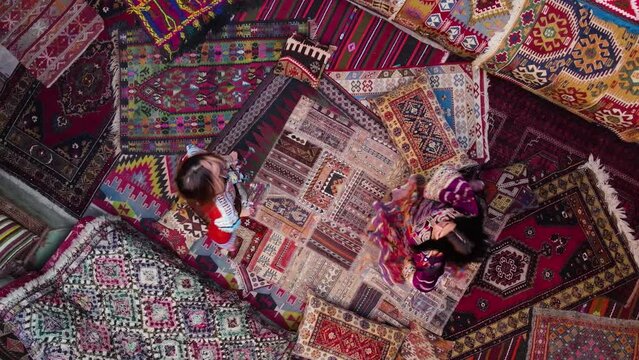 Two girls spinning on national carpets of Turkey in Cappadocia