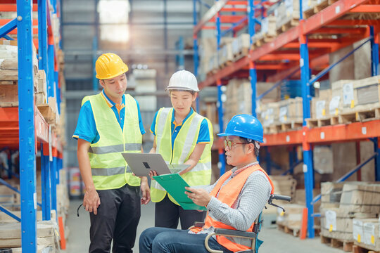 The supervisor is handicapped with a wheelchair inspecting the work background in warehouse.logistic  business export ,Warehouse worker checking packages on store