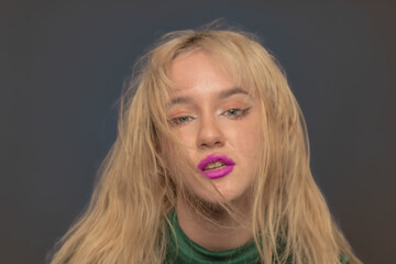 Young blond LA citizen poses in studio wearing a green leotard and jeans.