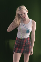 Young LA citizen in designer tank top and short plaid skirt poses in studio in a casual way.