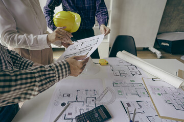 
Engineering team meeting for colleagues discussing and reviewing blueprints at desk in office...
