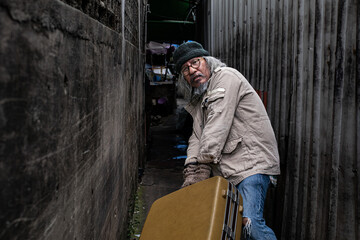 Asian poverty homeless man walk dragging large suitcase in narrow alley find for rest, poor man...