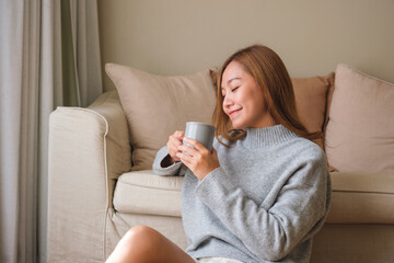 Portrait image of a beautiful young asian woman drinking hot coffee and relaxing at home