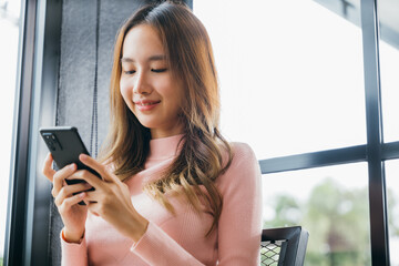 Happy beautiful female typing text message on smart phone device and enjoyment lifestyle with social networking media, Asian young woman using mobile phone at cafe coffee shop to shopping online