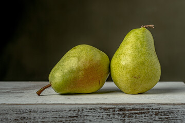 Two ripe green pears placed side by side. Close-up view showcasing the fresh textures and vibrant...