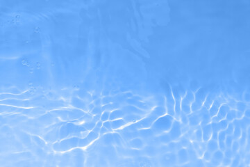 Bluewater waves on the surface ripples blurred. Defocus blurred transparent blue colored clear calm water surface texture with splash and bubbles. Water waves with shining pattern texture background.