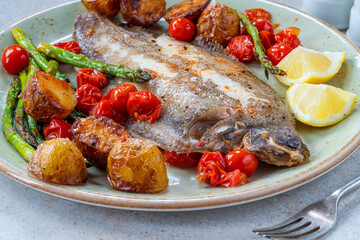 Lemon sole baked with potatoes, baby tomatoes and asparagus
