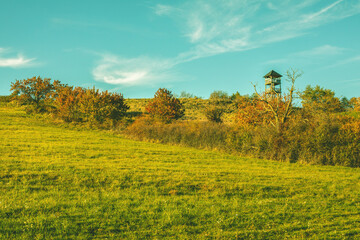 Watchtower on the green meadow on a sunny day.Autumn landscape.