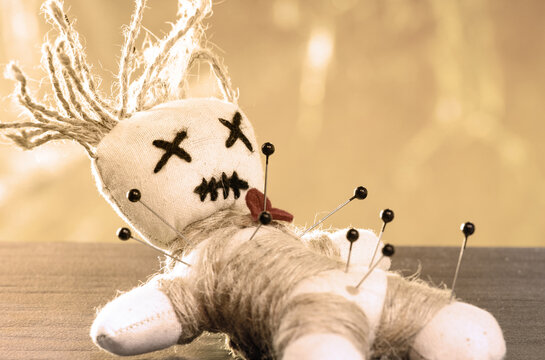Close-up of a voodoo doll, needles stuck in it.