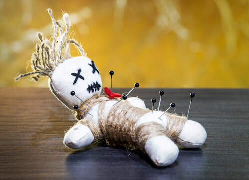 Close-up of a voodoo doll, needles stuck in it.