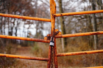 A barred gate chained with a padlock blocks the nature forest walking path