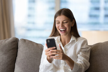 Cheerful cellphone user girl excited with good news, success, win, reading text message on mobile...