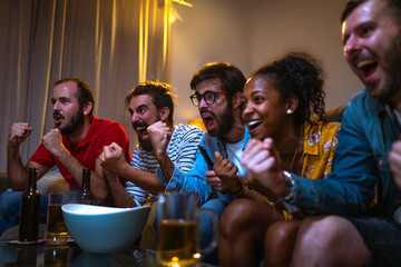 Group of friends watching football game on tv celebrating team victory. Soccer fans celebrating team scoring goal.