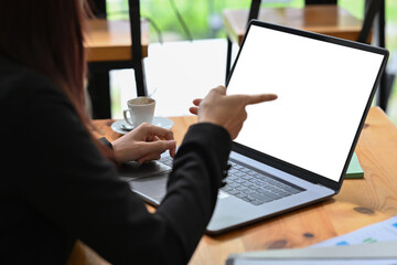 Millennial Asian businesswoman pointing on laptop screen, Empty screen of laptop, Business and financial concept.