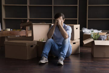 Stressed frustrated former home owner leaving flat, apartment, sitting at mess of cardboard boxes...