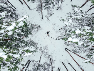 a man is lying in the snow among the pines, top view
