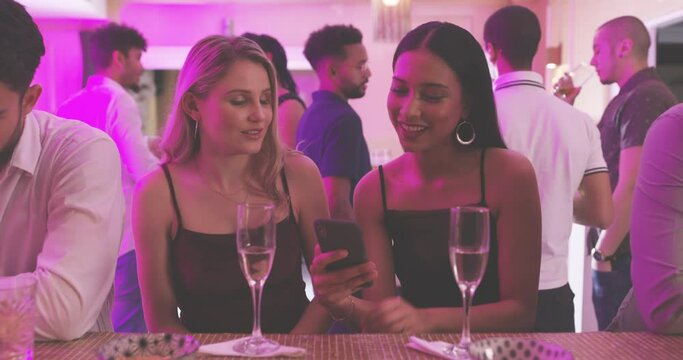 Phone, social media or friends gossip at a party, social event or gathering laughing at memes or online content. Smile, champagne or happy young women share, talking or speaking of entertainment news