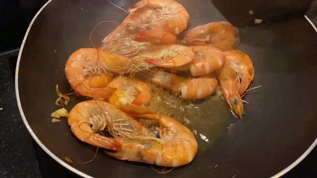 shrimps are fried in a frying pan with garlic