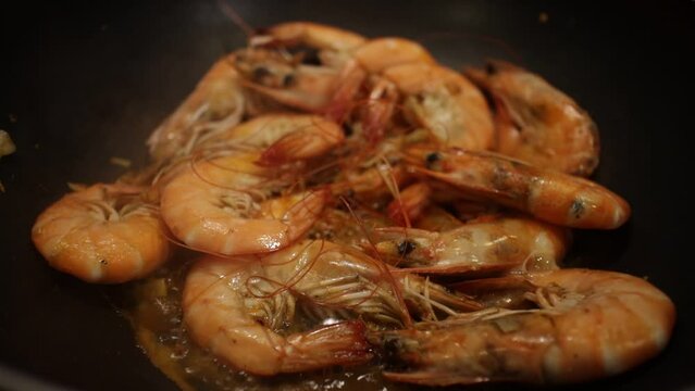 shrimps are fried in a frying pan with garlic