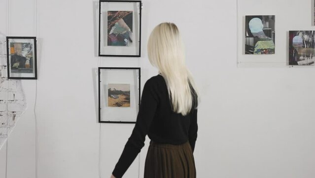 Beautiful blonde in the art gallery. A woman looks at the work of a contemporary artist.