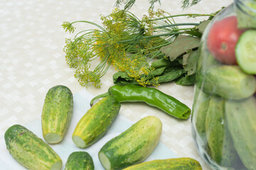 Cucumbers with green hot pepper on the table with glass jar with pickled vegetables cucumber and...