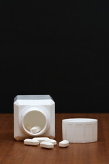 White open prescription medication container tablets wooden top black background copy space