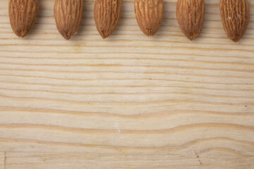 Wooden textured backgroun with roasted almonds on the top edge