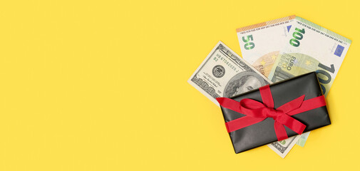 black gift box with a cash money on a yellow background. Festive background. Concept of presents,...