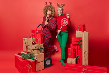 Happy winter holidays concept. Two women stand next to each other keep fingers crossed make wish...
