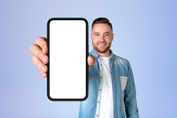 Smiling man holding a large phone mock up blank display on blue background