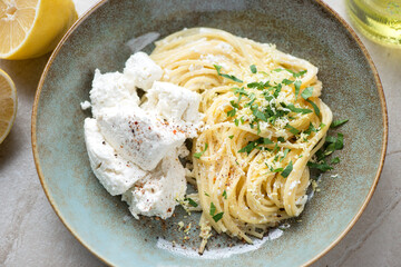 Rustic plate with spaghetti, ricotta cheese, lemon zest and chopped greens, close-up, horizontal shot