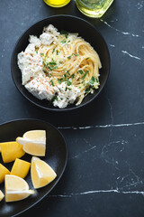 Bowl of lemon and ricotta spaghetti on a black marble background, vertical shot with space, top view