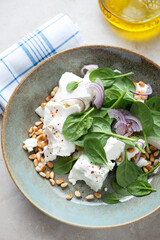 Salad with spinach leaves, feta cheese, pine nuts and red onion, middle close-up, elevated view, vertical shot