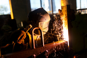 Workshop of the shipyard. Close-up. The welder works with welding in a protective mask.