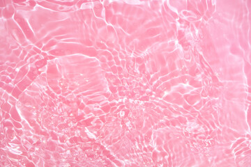 Fototapeta premium Defocus blurred transparent pink colored clear calm water surface texture with splashes and bubbles. Trendy abstract nature background. Water waves in sunlight with copy space. Pink watercolor shining