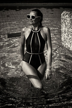 A Vintage Photo Of A Woman In A Black Swimsuit And White Sunglasses Coming Out Of The Pool