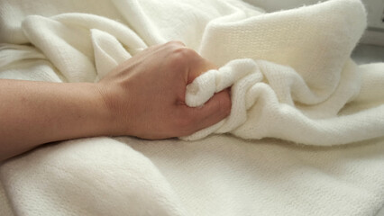 female's hand on the fabric of white plush cloth with soft nap. Clothing industry concept, slow motion. woman checking the quality of clothes, enjoys the soft pleasant texture of the fabric