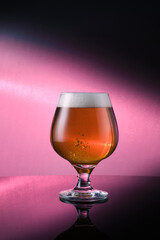 a glass of beer with purple gradient background