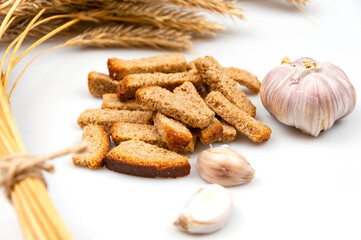 Rye crackers with garlic on a white background with ripe ears of rye.