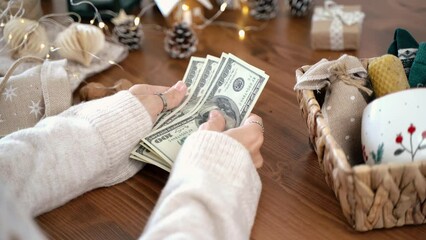 Girl counting US Dollar bills, and planning expenses for Christmas. Woman doing budget, estimating money balance for shopping spree. Female accountant paying taxes. Girl counting Christmas gifts.