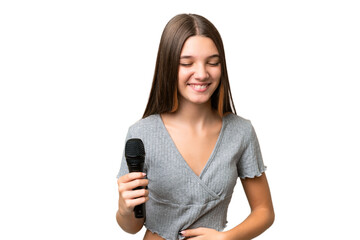 Teenager singer girl picking up a microphone over isolated background smiling a lot