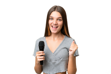 Teenager singer girl picking up a microphone over isolated background celebrating a victory in winner position