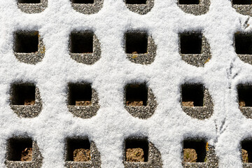 Concrete drain grate covered with snow in winter