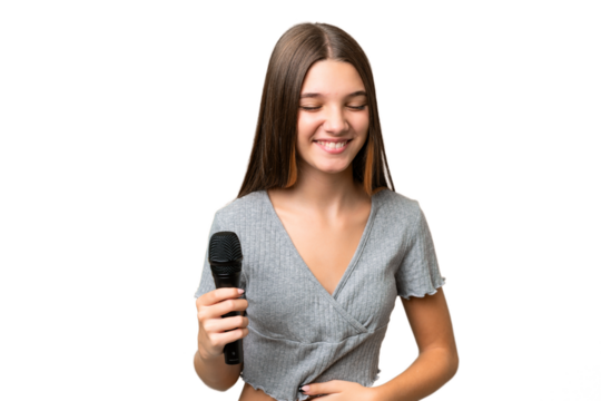 Teenager singer girl picking up a microphone over isolated background smiling a lot
