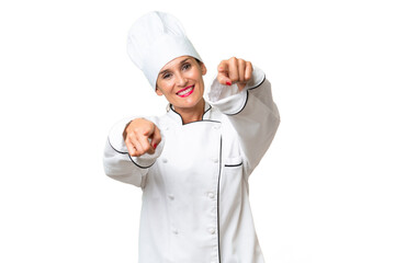 Middle-aged chef woman over isolated background points finger at you while smiling