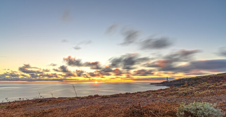 Long exposure sunrise of rough coastline and lighthouse