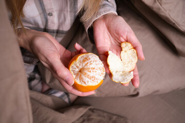 Young woman peels a ripe juicy tasty tangerine. Healthy food, organic fruits. Natural vitamins, raw materials for food
