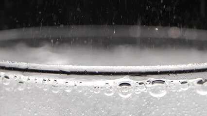 A glass of sparkling water on a black background. Bubbles come out of the glass. Pure mineralized water with gas.
