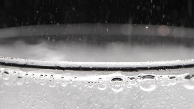 A glass of sparkling water on a black background. Bubbles come out of the glass. Pure mineralized water with gas.